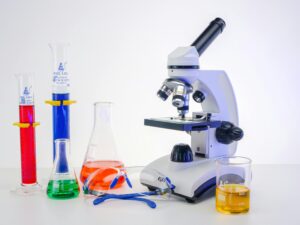 A vibrant collection of laboratory tools including a microscope and glassware with colorful liquids.